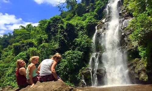Visitors resting on a rock beside a Marangu waterfall