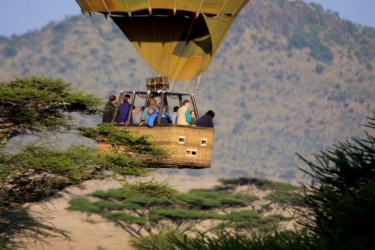 Passengers riding a hot air balloon basket over the Serengeti