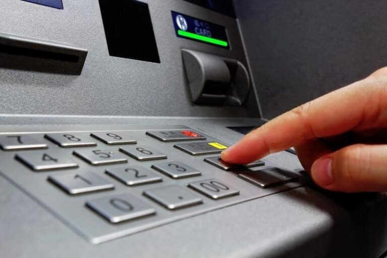 A hand using the keypad of an ATM to withdraw cash